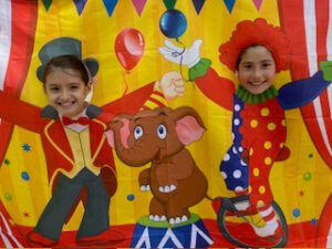 Children posing at a picture cutout of a circus scene.