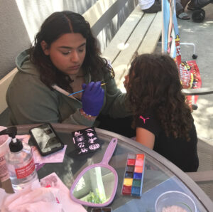 A child receiving a face painting at the face paint table.