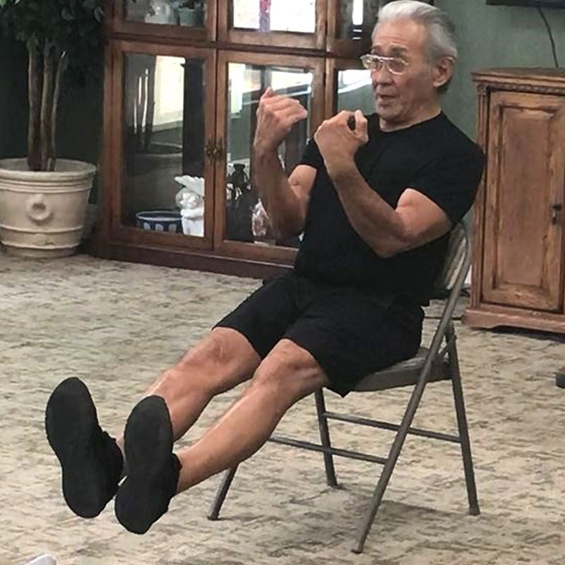 An instructor leading an exercise while sitting in a chair.